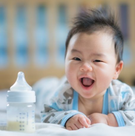 Smiling baby next to bottle