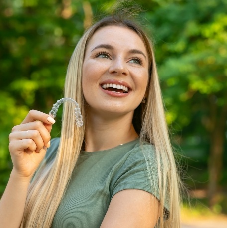 Smiling woman holding a clear correct aligner tray