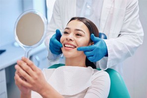 Young woman in the dental chair looking at her smile in a mirror
