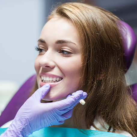 Dentist looking at a patient smiling with dental crowns in Soldotna