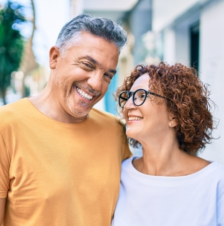 Man and woman smiling after dental implant tooth replacement