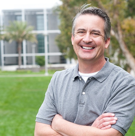 man smiling outside with arms crossed