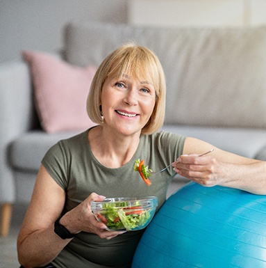 older woman eating salad in living room 