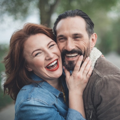 Man and woman with flawless smiles after replacing missing teeth