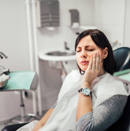 Woman holding cheek in pain before root canal treatment