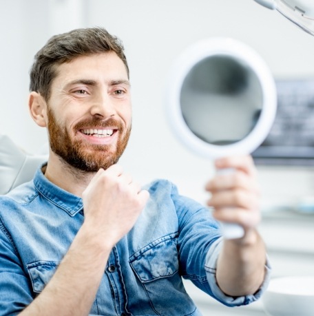 Man looking at himself in the mirror after smile makeover