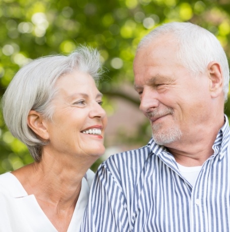 Older man and woman smiling after tooth extractions