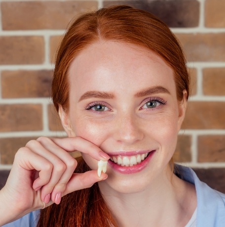 Woman holding a tooth after extraction