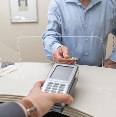 An adult man paying the cost of veneers