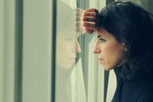 A woman unsure if she should visit an emergency dentist.