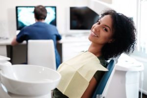 Woman smiling during her dental appointment with dental assistant